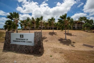 DHHL sign in front of palm trees.
