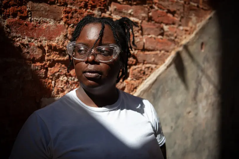 A Black woman with glasses looks off-camera.